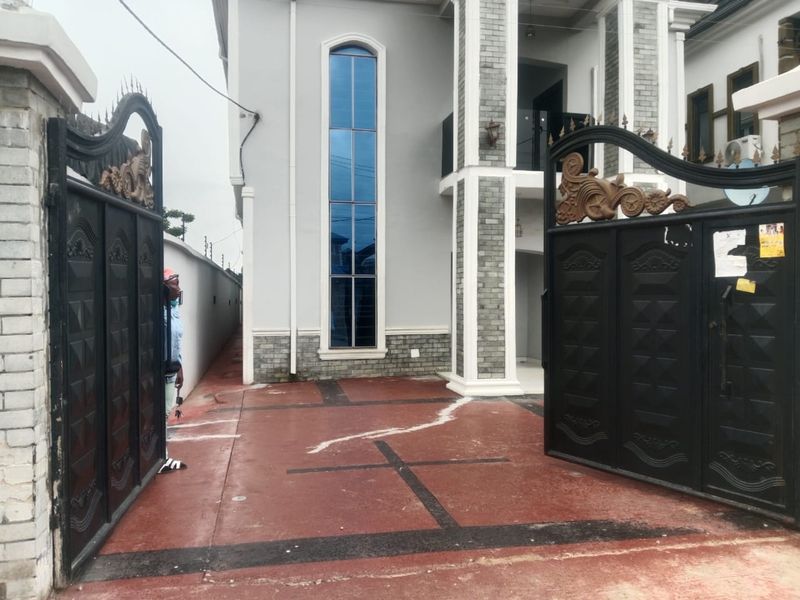 Completed duplex behind a black wrought-iron gate with grey stone cladding and a tall arched window
