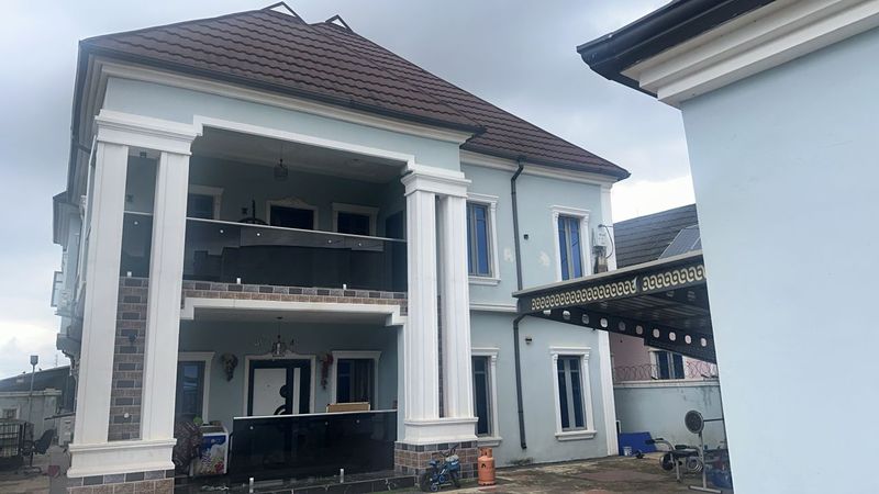 Two-storey house with white columns and a glass balcony