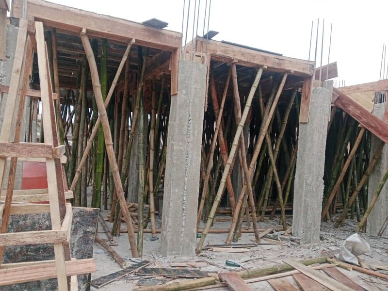 Slab formwork resting on bamboo props between concrete columns