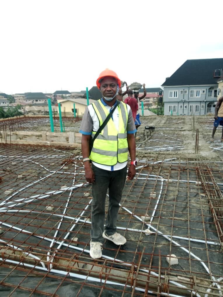 Team member in a hard hat and safety vest standing on foundation reinforcement
