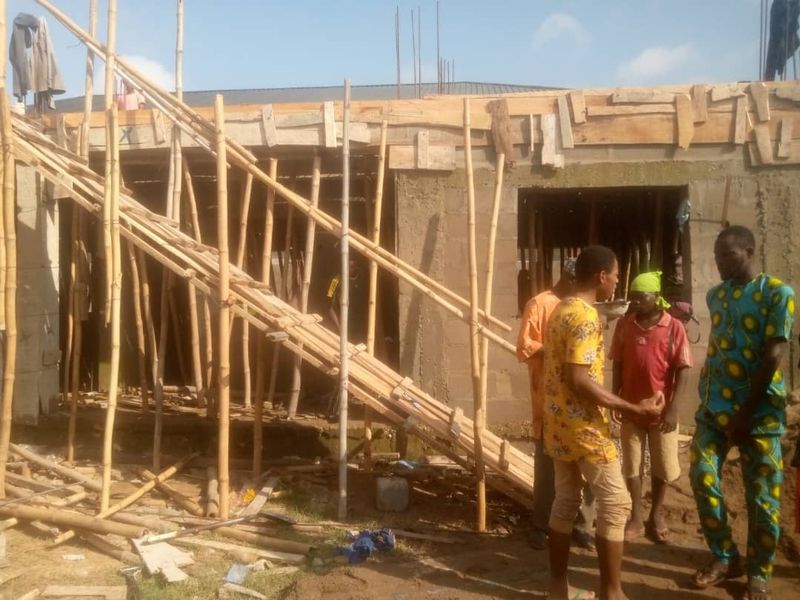 Site meeting between three people in front of a building under construction